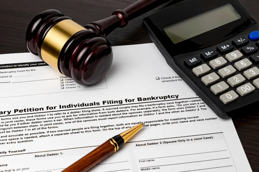 Wooden judge’s gavel beside a calculator on bankruptcy paperwork for an individual filing, illustrating chapter 13 plan payment estimation and consumer bankruptcy costs.