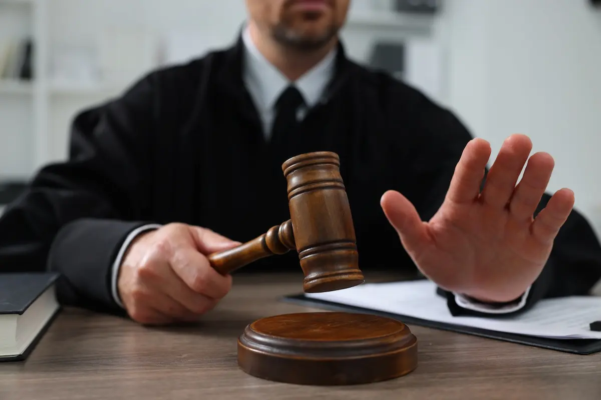 Image of a judge with a gavel holding his hand out to stop a group of creditors rushing towards him, symbolizing how bankruptcy can stop creditors.